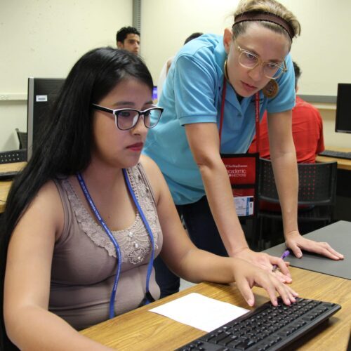 Volunteer tutor helps a student who is using a computer